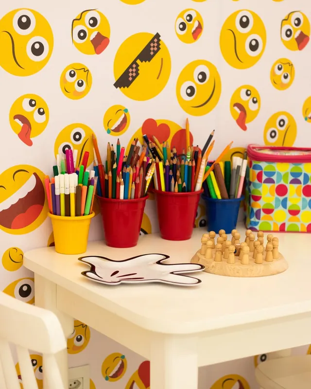 Sala de atendimento com parede de emojis, lápis coloridos e jogos